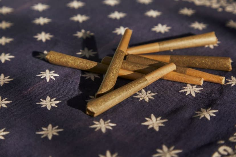 Verschillende bruine voorgedraaide joints liggen op een donkerblauwe doek met witte sterren in het zonlicht.