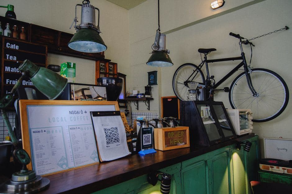 Gezellige sfeer bij de houten bar van een coffeeshop met een menu, retro lampen en een fiets aan de muur.