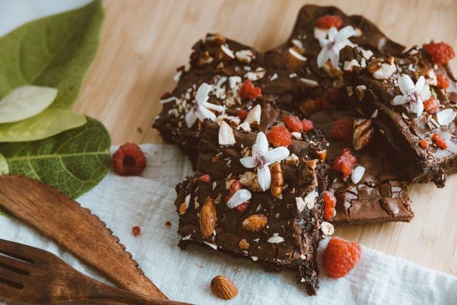 Chocoladebrownies met frambozen, amandelen en bloemetjes, heerlijk als zoete snack voor bij een warme wietthee.