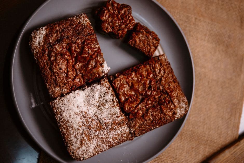 Versgebakken wietbrownies met poedersuiker op een grijs bord.