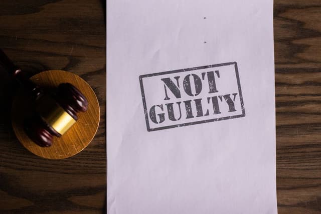 Een rechtershamer en papier met het stempel NOT GUILTY op een houten tafel tijdens de juridische strijd in Almelo.