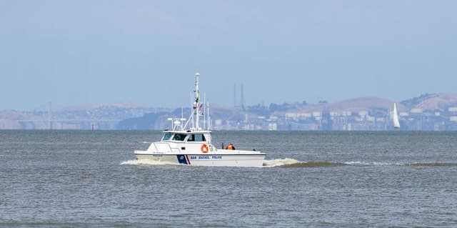 Een witte politieboot vaart over het water tijdens een klopjacht op zee.