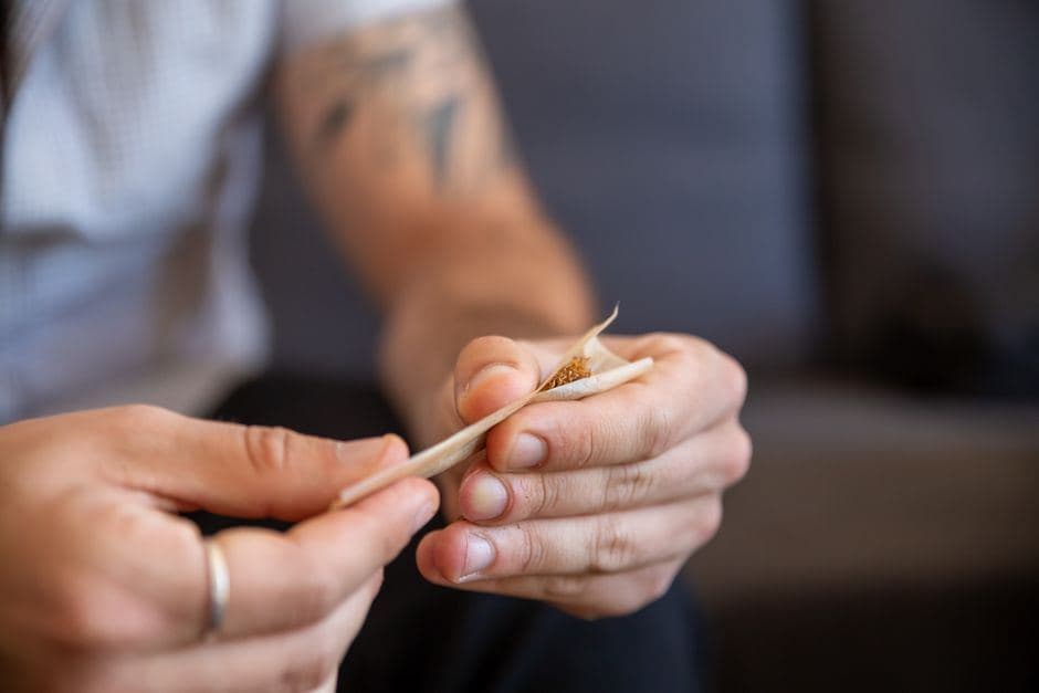 Een persoon rolt aandachtig een joint met wiet in een vloeitje.